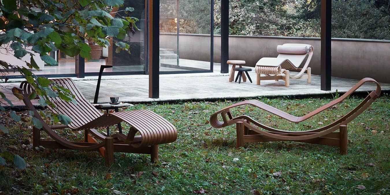 Drei h&ouml;lzerne, geschwungene Liegen stehen auf einer Terrasse.